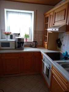 a kitchen with wooden cabinets and a sink and a window at Ferienwohnung LAURA in Böbrach