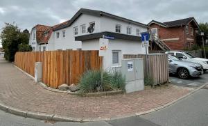 a white house with a wooden fence on a street at Ferienapartment Stemmert in Gelting +2 photos