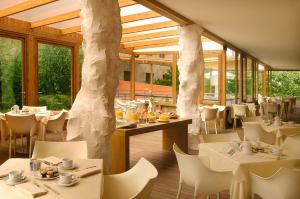 un restaurante con mesas y sillas blancas y ventanas en Hotel Abitart en Roma