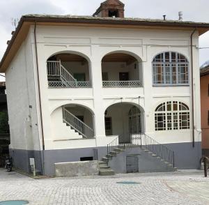 un grande edificio bianco con tre finestre ad arco di Appartamento in centro Nus a Nus