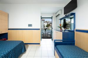 um quarto com 2 camas e uma cozinha com uma mesa em Hotel Olanda em Lido di Jesolo