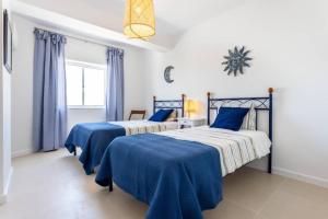 2 letti in una camera da letto con blu e bianco di Cozy ap renovado 1ª linha de Praia - Armação Pêra ad Armação de Pêra