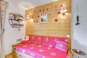 a bedroom with a pink bed and a wooden wall at Le cœur des Evettes - Apt aux pieds des pistes in Flumet +9 photos