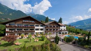 a hotel with a pool and mountains in the background at Hotel Appartement Inge in Tirolo
