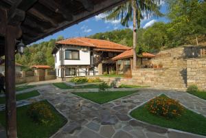 a house with a stone wall and a yard at Complex Balgarka in Tryavna