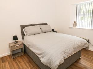 a bedroom with a bed with a night stand and a window at Heatherbank in Garelochhead