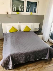 - une chambre avec un grand lit et 2 oreillers jaunes dans l'établissement Apartment Oase- Kaiserslautern, à Kaiserslautern