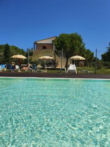 einen Pool mit Wasser, Stühlen und Sonnenschirmen in der Unterkunft La Finestra sul Conero Apartments in Numana