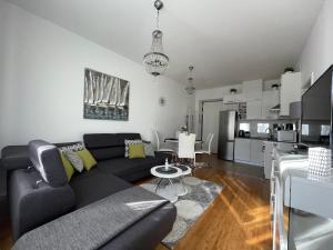 salon z czarną kanapą i kuchnią w obiekcie Marimar apartments w Zagrzebiu