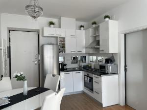 - une cuisine avec des placards blancs, une table et des chaises dans l'établissement Marimar apartments, à Zagreb