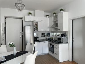 kuchnia z białymi szafkami, stołem i krzesłami w obiekcie Marimar apartments w Zagrzebiu