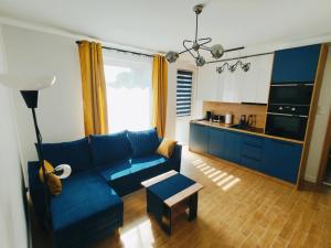 a living room with a blue couch and a kitchen at ApartHome K8 Centrum Sulęcin in Sulęcin