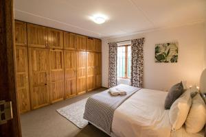 Schlafzimmer mit einem Bett mit Holzschränken und einem Fenster in der Unterkunft Garden Cottage in Graaff-Reinet