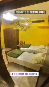 two beds in a room with yellow walls at Pousada Agronomia in Porto Alegre