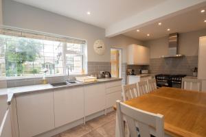 a kitchen with white cabinets and a wooden table at Sherwood in Birdham