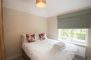 a bedroom with a bed with white sheets and a window at Sherwood in Birdham