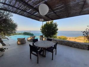 un patio con mesa y sillas y vistas al océano en Villa Lithos, en Kími