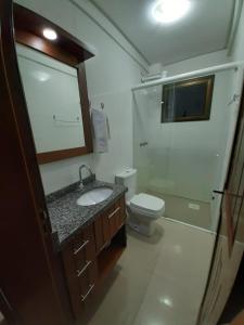 a bathroom with a sink and a toilet and a mirror at Apart-Hotel Pacífico in Tramandaí
