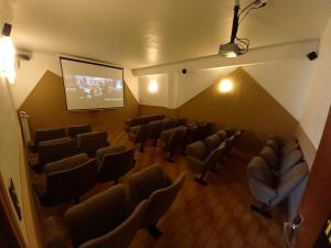 une grande chambre avec des chaises et un écran de projection dans l'établissement Auberge La Prairie, à Matemale