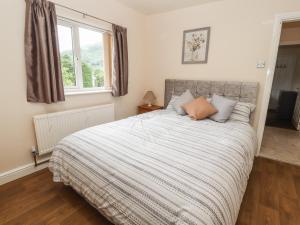 - une chambre avec un grand lit et une couverture rayée dans l'établissement Awel Y Berwyn, à Oswestry