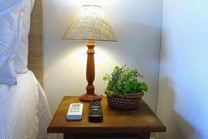 a lamp on a table next to a bed with a plant at Solar Agua Flats Elegance Flat in Pipa +39 photos