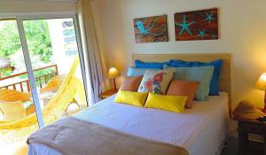 a bedroom with a bed with pillows and a balcony at Solar Agua Flats Elegance Flat in Pipa