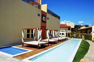 a group of chairs sitting next to a swimming pool at Solar Agua Flats Elegance Flat in Pipa