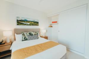 a white bedroom with a bed and two lamps at Domaine de Grand Baie in Grand-Baie