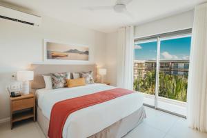 a bedroom with a large bed and a large window at Domaine de Grand Baie in Grand-Baie