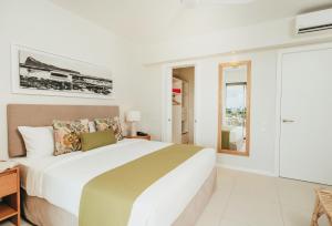 a white bedroom with a large bed and a window at Domaine de Grand Baie in Grand-Baie