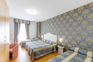 um quarto de hotel com três camas e um sofá em LAERTE PALACE HOTEL em Mogliano Veneto