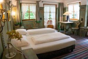 a bedroom with two beds and a table and windows at Hotel Schrenkhof in Unterhaching