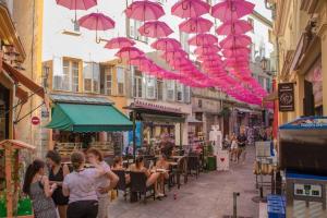 a group of people walking down a street with pink umbrellas at La loveroom bdsm grassoise "La chambre des désirs" in Grasse