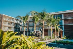 an apartment building with palm trees and a swimming pool at Domaine de Grand Baie in Grand-Baie