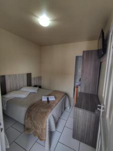 a small bedroom with two beds and a table at Hotel Maichel in Erval Velho