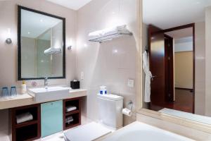 a bathroom with a sink and a toilet and a mirror at Tianjin Crown International Apartment in Tianjin