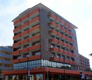un edificio alto de color rojo con muchas ventanas en Hotel Palazzo Caveja en Rímini