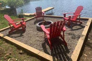 3 chaises rouges et un foyer extérieur près de l'eau dans l'établissement Large family house on the lake, à Hewitt