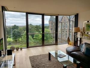 a living room with a couch and a large window at Quartermile Luxury Landing Apartment in Edinburgh