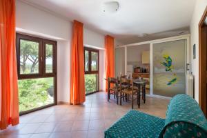 a living room with orange curtains and a table and chairs at Agriturismo Le Vecchie Scuole in Campiglia Marittima