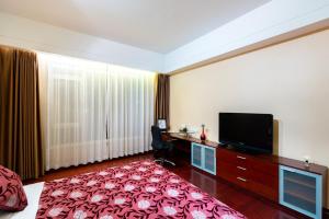 a hotel room with a flat screen tv and a desk at Tianjin Crown International Apartment in Tianjin