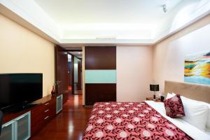 a bedroom with a bed and a flat screen tv at Tianjin Crown International Apartment in Tianjin
