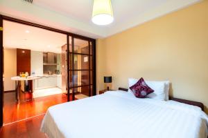 a bedroom with a large white bed and a bathroom at Tianjin Crown International Apartment in Tianjin