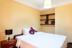 a bedroom with a large white bed and a lamp at Tianjin Crown International Apartment in Tianjin