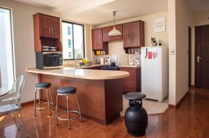 a kitchen with a counter and a refrigerator and stools at Apartamento Mira 1 in Cochabamba