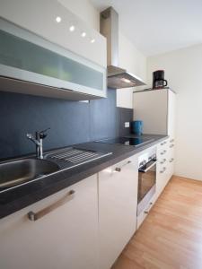 een keuken met witte kasten en een wastafel bij Ferienwohnung Fernblick in Saarbrücken