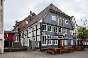 a black and white building with tables and umbrellas at Alte Ratsschänke in Geseke