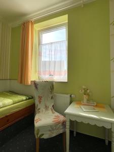 Mały pokój z łóżkiem, krzesłem i oknem w obiekcie Haus Toskana w mieście Bad Frankenhausen