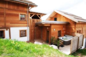 een houten huis met een bad op een terras bij Les Adrets in Gérardmer