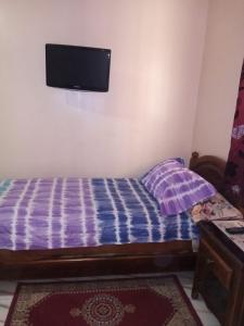 1 dormitorio con 1 cama y TV en la pared en Hotel Aswan, en Oujda